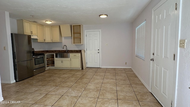 kitchen with light tile patterned floors, cream cabinets, stainless steel appliances, and sink