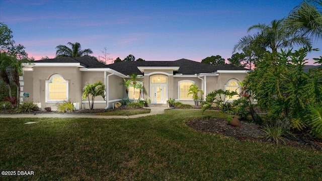 view of front facade with a lawn and stucco siding