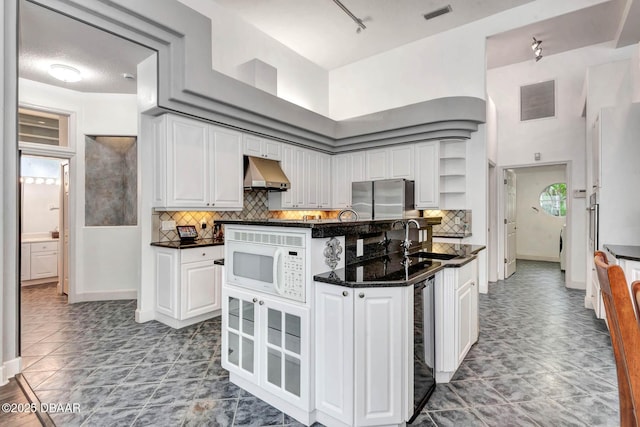 2 Creek Bend Way, Ormond Beach, FL 32174 - kitchen with under cabinet range hood, freestanding refrigerator, white microwave, white cabinetry, and tasteful backsplash