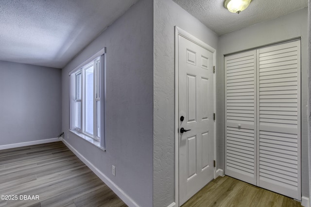 hall with a textured ceiling and light wood-type flooring