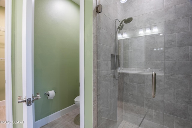 bathroom featuring a shower with shower door and toilet