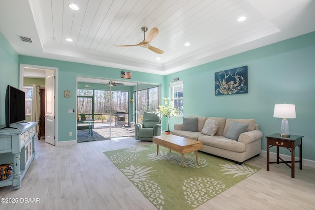 living room with wood ceiling, a tray ceiling, light hardwood / wood-style flooring, and ceiling fan