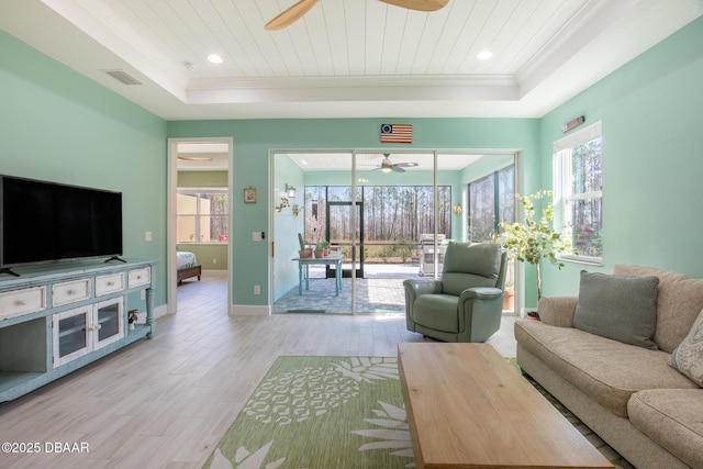 living room featuring wood ceiling, crown molding, light wood-type flooring, a raised ceiling, and ceiling fan