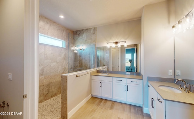 bathroom with hardwood / wood-style flooring, vanity, and tiled shower