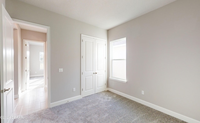 unfurnished bedroom featuring light carpet and a closet