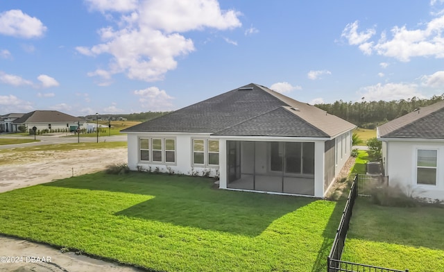 rear view of house featuring a sunroom and a lawn