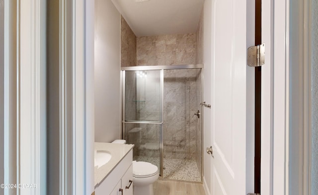 bathroom featuring vanity, wood-type flooring, an enclosed shower, and toilet