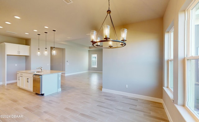 kitchen with light hardwood / wood-style flooring, stainless steel dishwasher, pendant lighting, a kitchen island with sink, and white cabinets