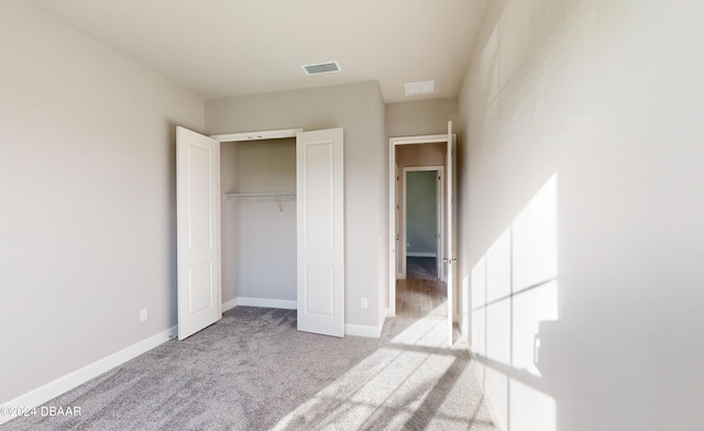 unfurnished bedroom featuring light colored carpet and a closet