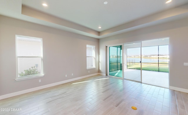 empty room with a raised ceiling and light wood-type flooring