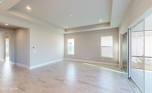 unfurnished room with light hardwood / wood-style floors and a raised ceiling