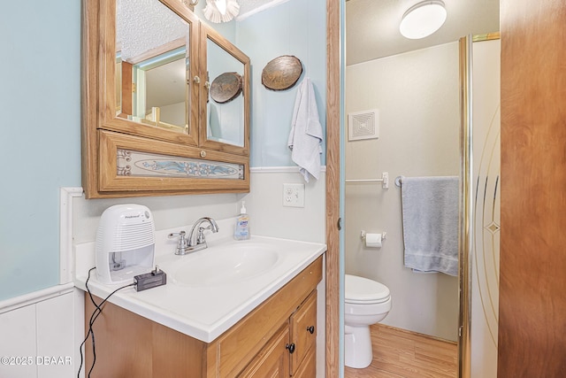 bathroom with toilet, wood finished floors, and vanity