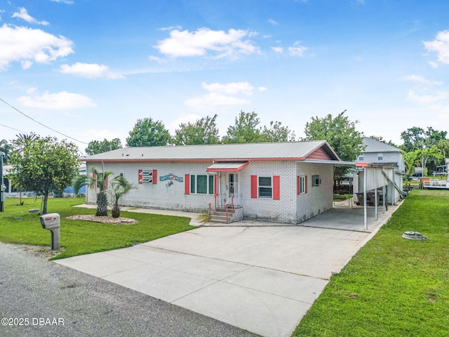 view of front of house featuring brick siding, driveway, a carport, and a front lawn