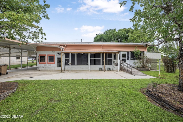 rear view of property featuring a yard, fence, a patio area, and a sunroom