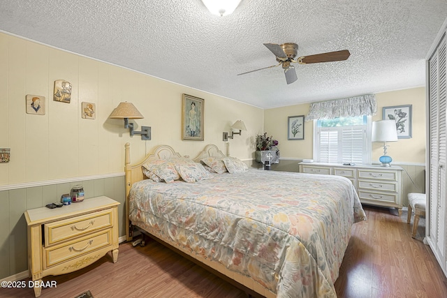 bedroom featuring a textured ceiling, ceiling fan, and wood finished floors