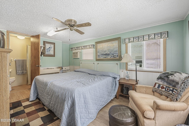 bedroom featuring ensuite bath, a textured ceiling, ceiling fan, and wood finished floors