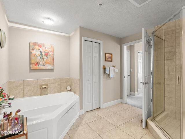 2403 S Atlantic Ave Unit 410, Daytona Beach, FL 32118 - full bath featuring tile patterned floors, a shower stall, a garden tub, a textured ceiling, and a closet