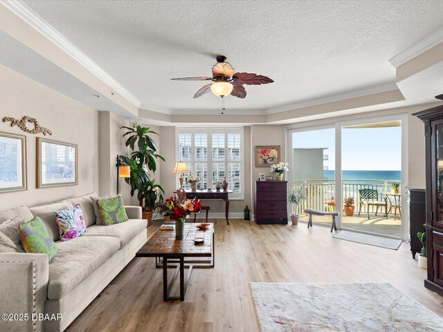 2403 S Atlantic Ave Unit 410, Daytona Beach, FL 32118 - living area featuring a tray ceiling, ceiling fan, crown molding, wood finished floors, and a water view