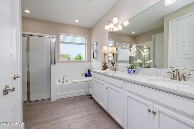 3013 Kenmare St, Ormond Beach, FL 32174 - full bathroom with double vanity, a shower stall, a garden tub, wood finished floors, and recessed lighting