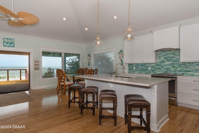 kitchen featuring stainless steel range with electric stovetop, white cabinets, sink, and a center island with sink