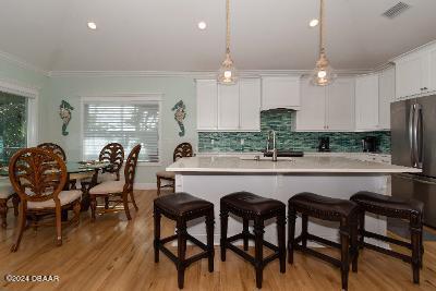 kitchen featuring crown molding, hanging light fixtures, decorative backsplash, white cabinetry, and stainless steel refrigerator