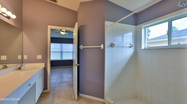 bathroom with a tile shower, tile patterned floors, a ceiling fan, vanity, and baseboards