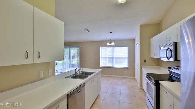 kitchen with stainless steel appliances, a sink, white cabinetry, light countertops, and decorative light fixtures