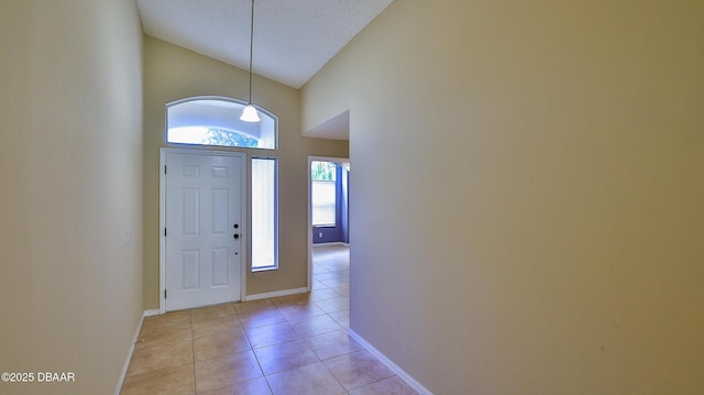 foyer with high vaulted ceiling, baseboards, and light tile patterned floors
