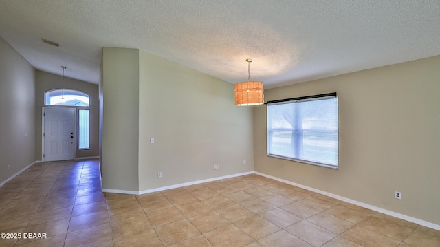 interior space featuring lofted ceiling, a textured ceiling, baseboards, and light tile patterned floors