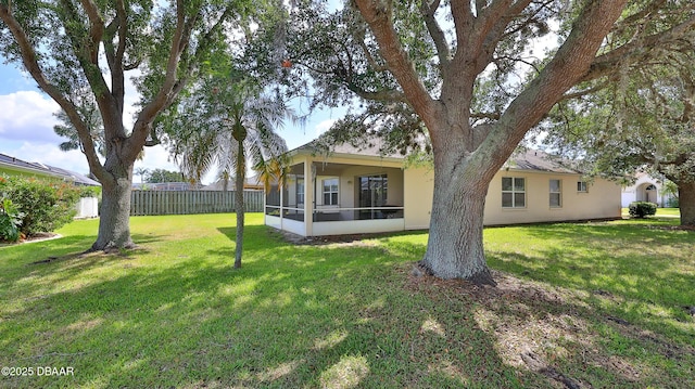 back of house with fence, a sunroom, a yard, and stucco siding