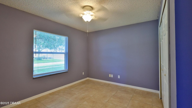 unfurnished room with ceiling fan, baseboards, a textured ceiling, and light tile patterned floors