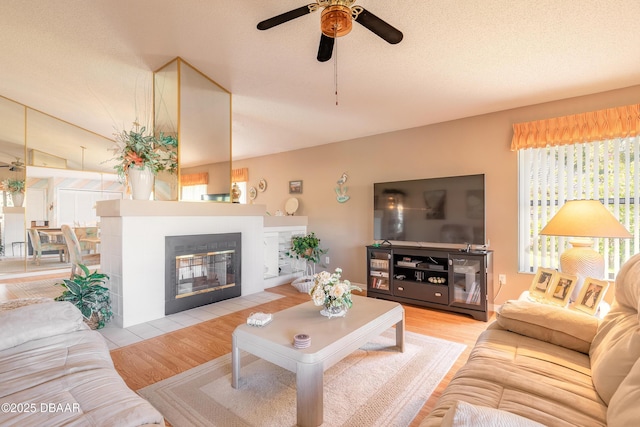 living room featuring ceiling fan, a textured ceiling, and light wood-type flooring