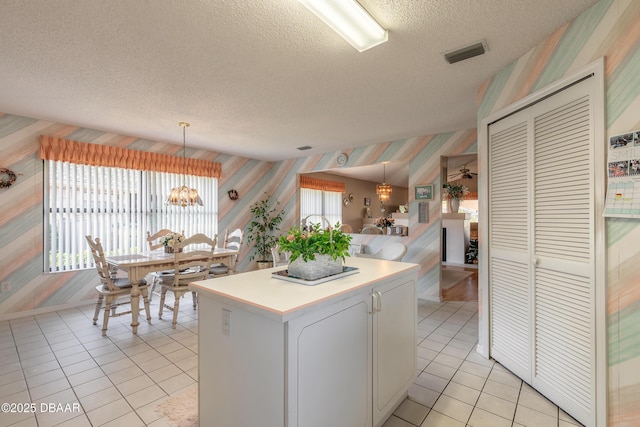 kitchen with decorative light fixtures, a notable chandelier, white cabinetry, and a textured ceiling