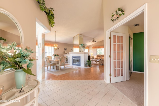 tiled foyer featuring vaulted ceiling, a tile fireplace, and ceiling fan with notable chandelier