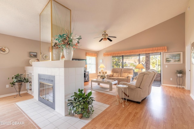 living room with vaulted ceiling, ceiling fan, light hardwood / wood-style flooring, and a brick fireplace