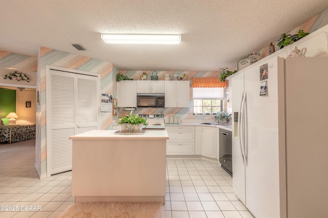 kitchen with a textured ceiling, light tile patterned floors, white cabinets, and black appliances