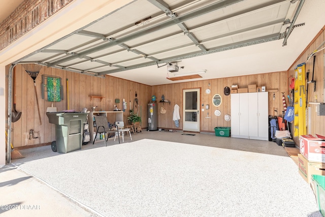 garage with electric water heater, a garage door opener, and wood walls