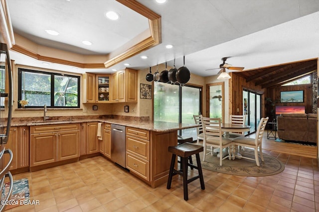 kitchen with kitchen peninsula, light stone counters, a kitchen breakfast bar, ceiling fan, and lofted ceiling