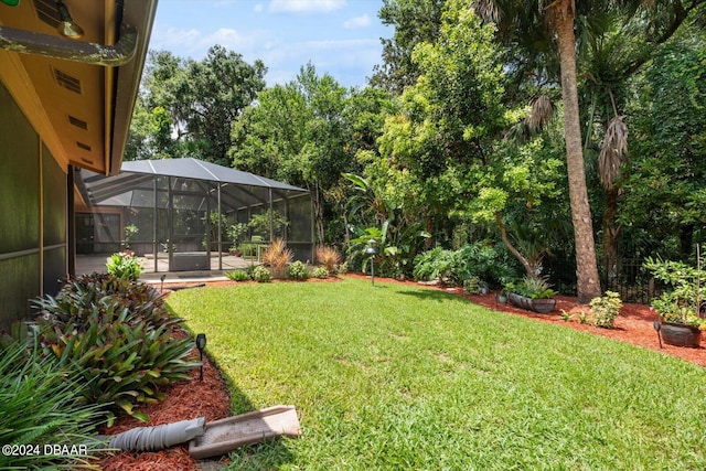 view of yard with glass enclosure and a patio