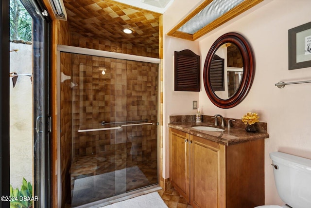 bathroom with vanity, tile patterned floors, toilet, and a shower with door