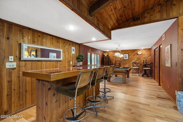 bar featuring lofted ceiling, a textured ceiling, wooden walls, billiards, and light hardwood / wood-style flooring