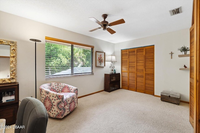 sitting room featuring a textured ceiling, carpet flooring, and ceiling fan