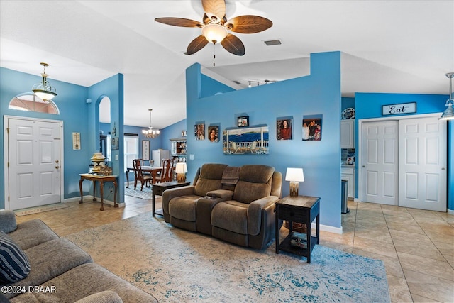 tiled living room with ceiling fan with notable chandelier and high vaulted ceiling