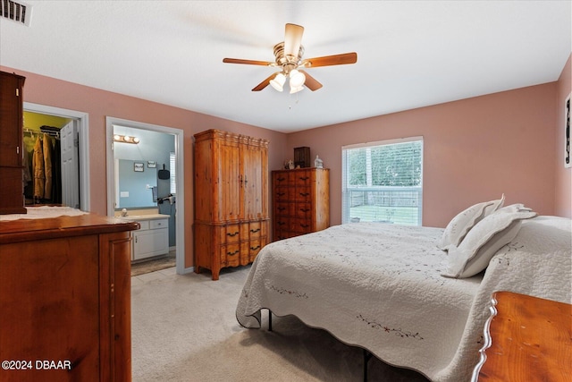 bedroom with ceiling fan, connected bathroom, a spacious closet, and light colored carpet