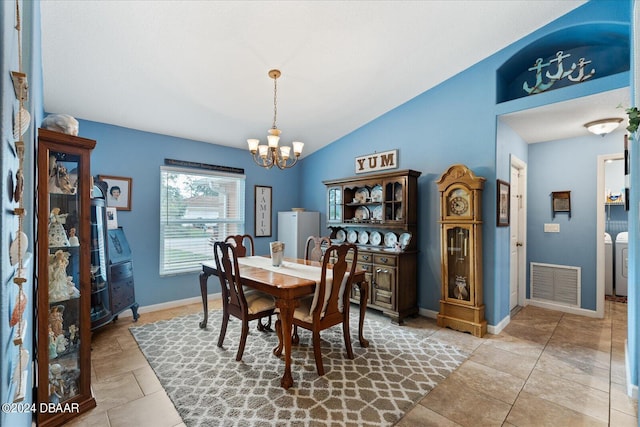 tiled dining space featuring vaulted ceiling, a chandelier, and washer and clothes dryer