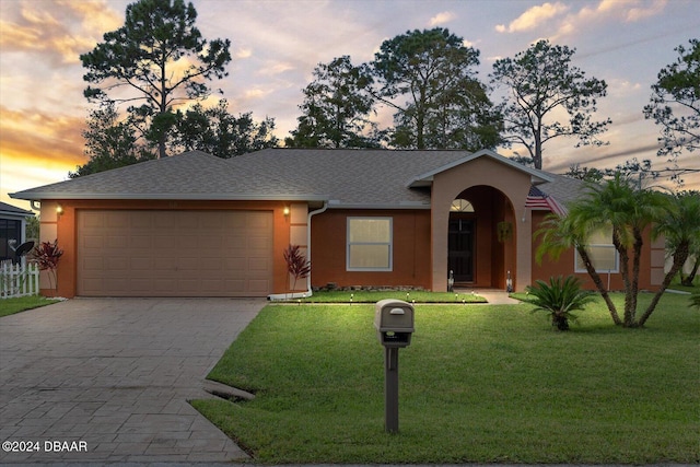 single story home with a garage and a yard