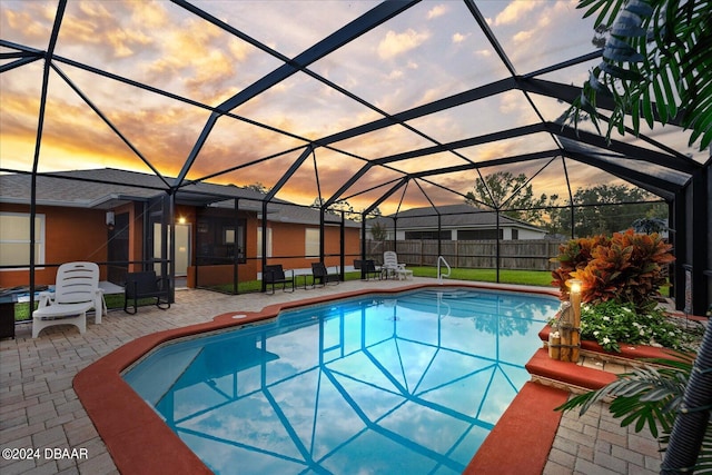 pool at dusk featuring a lanai and a patio area