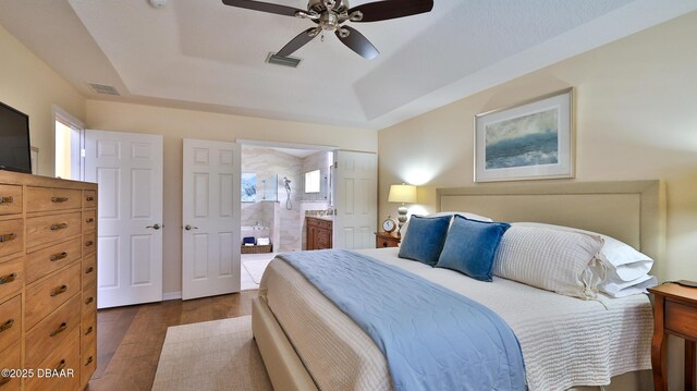 1453 Sunningdale Ln, Ormond Beach, FL 32174 - bedroom with dark wood-style flooring, a tray ceiling, visible vents, and ensuite bathroom
