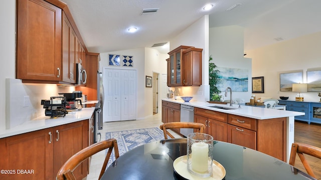 1453 Sunningdale Ln, Ormond Beach, FL 32174 - kitchen with visible vents, brown cabinetry, a sink, vaulted ceiling, and stainless steel appliances