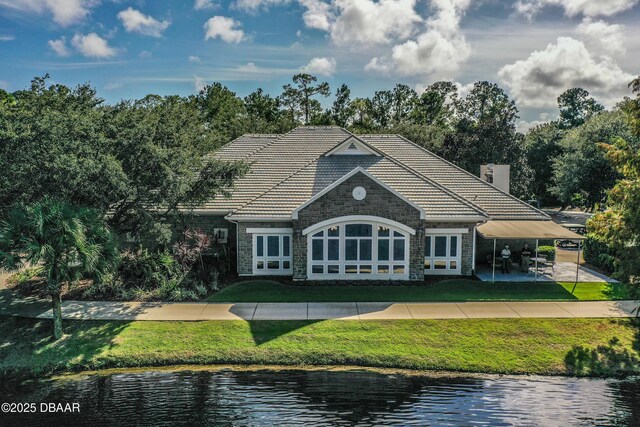 1453 Sunningdale Ln, Ormond Beach, FL 32174 - exterior space featuring a lawn, a water view, a tile roof, and stone siding